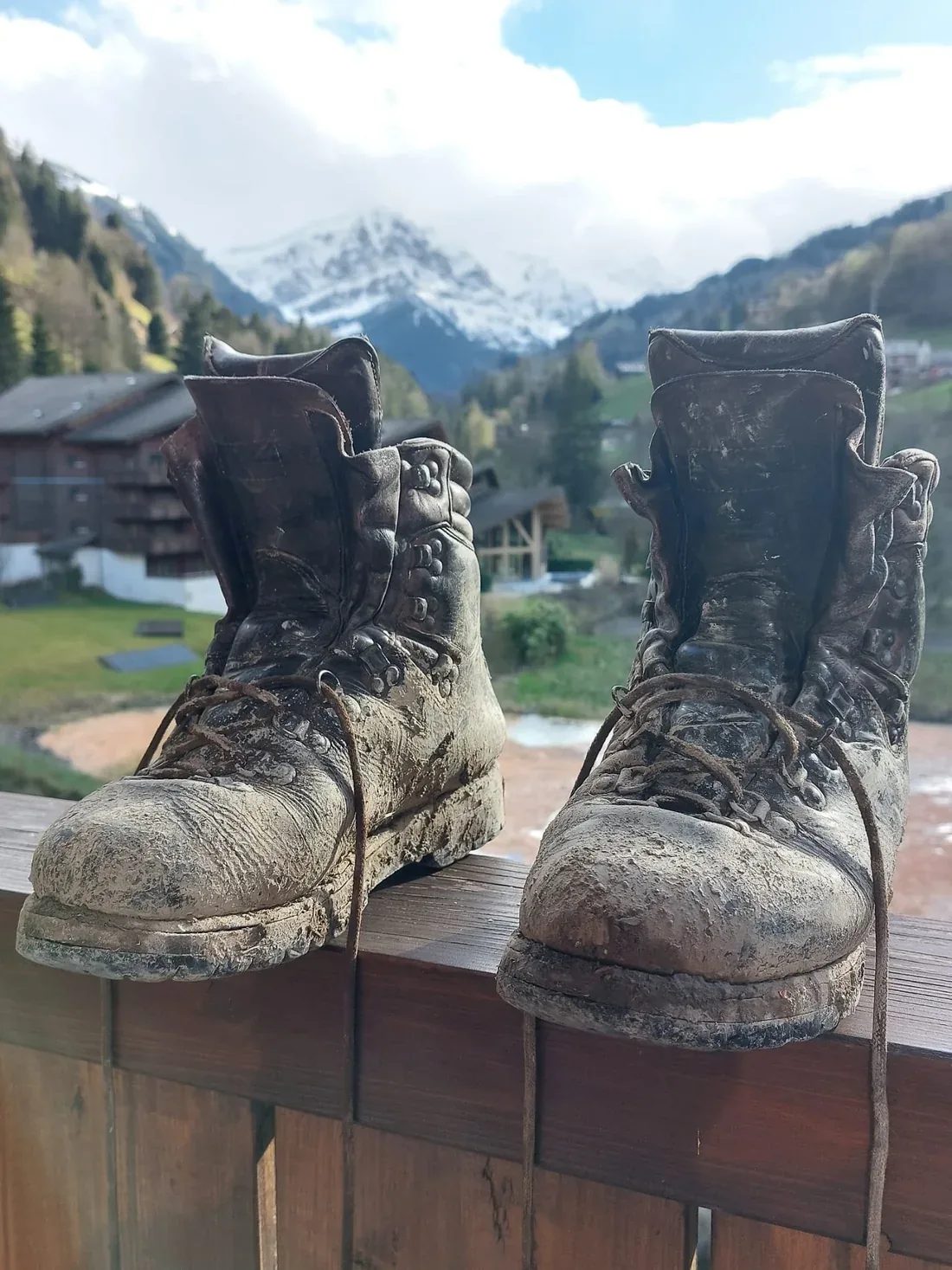 Mud-covered mountain boots with a snow mountain in the background