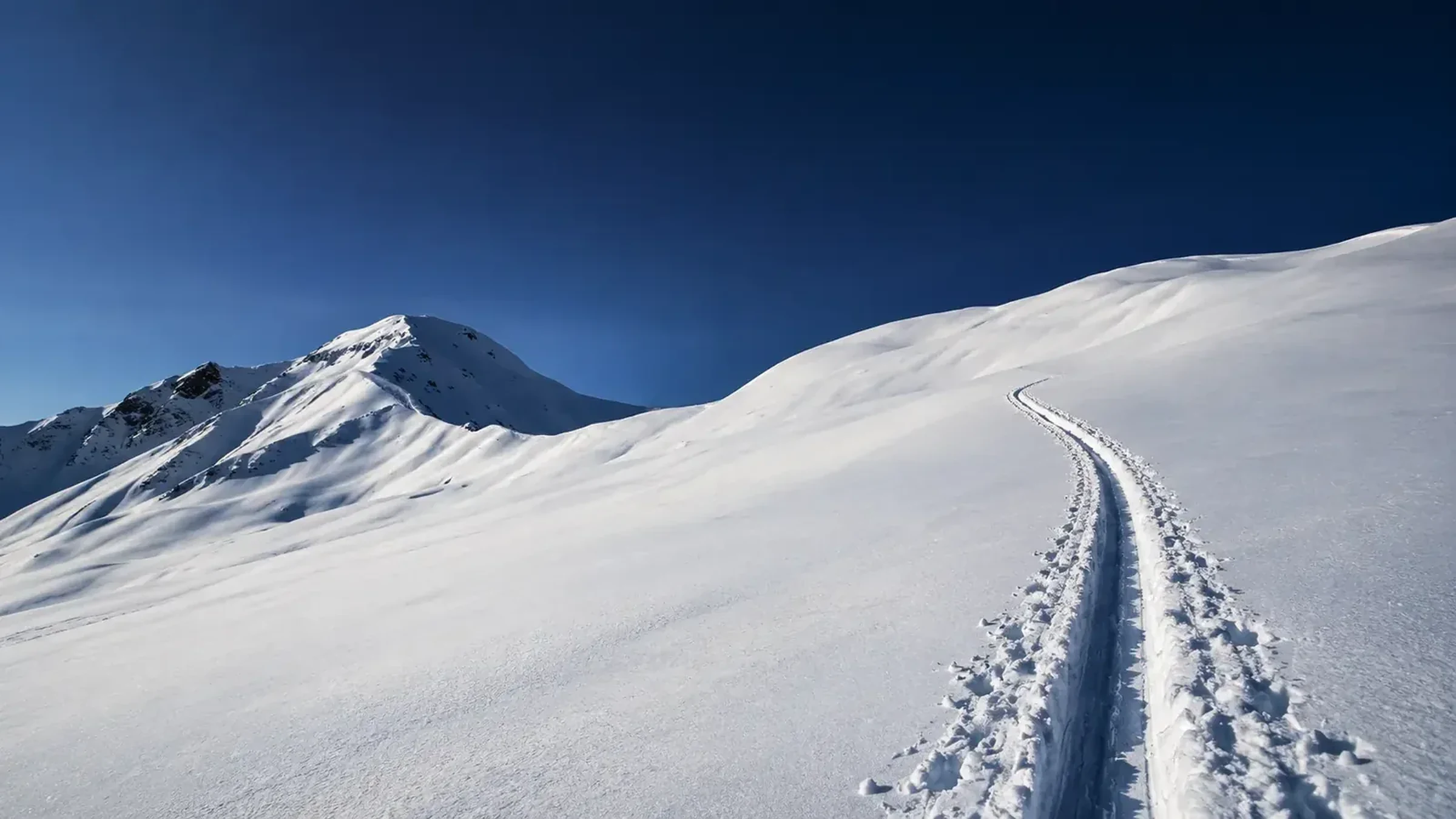 Snow-covered mountain slope with an ascending ski-tour track