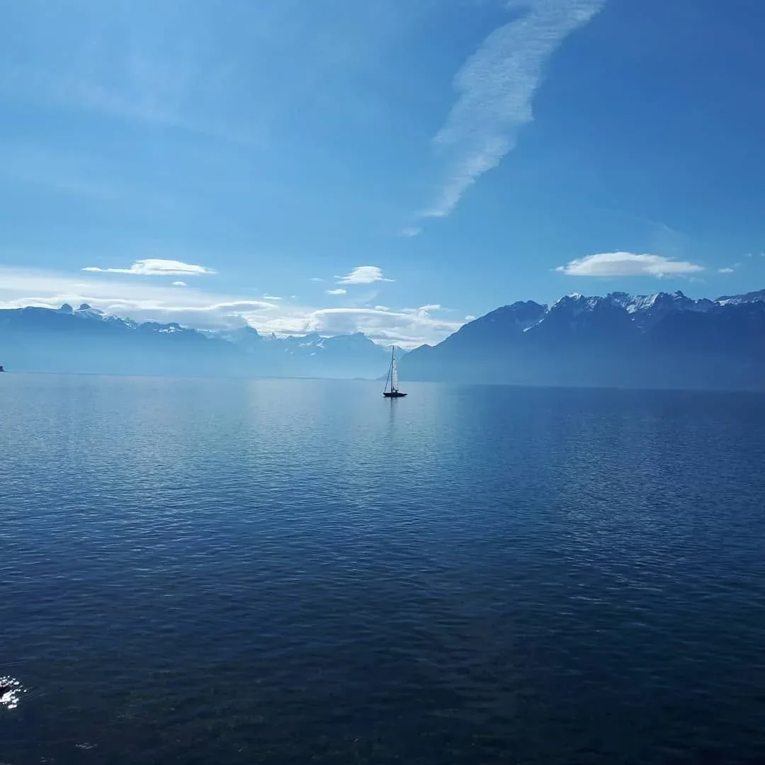 Lac Léman with a sailing boat and the Swiss Alps